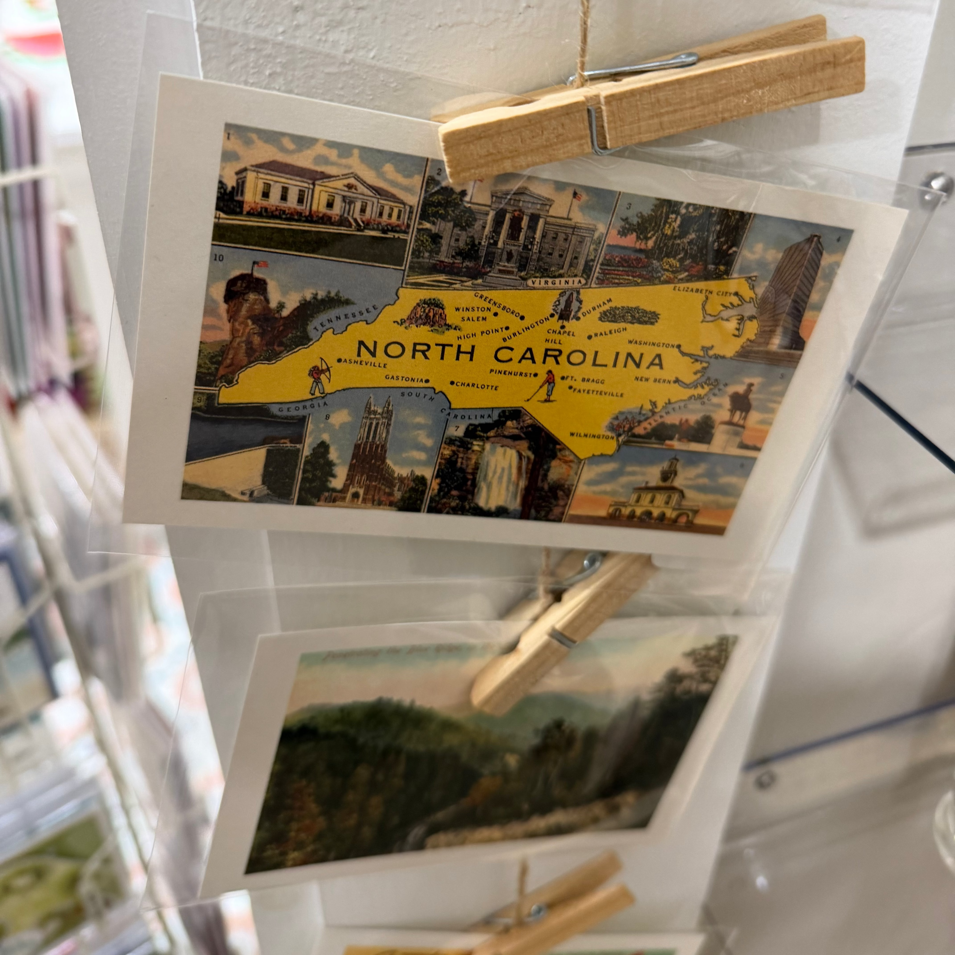 Collection of postcards featuring North Carolina on a display stand with wooden clips.